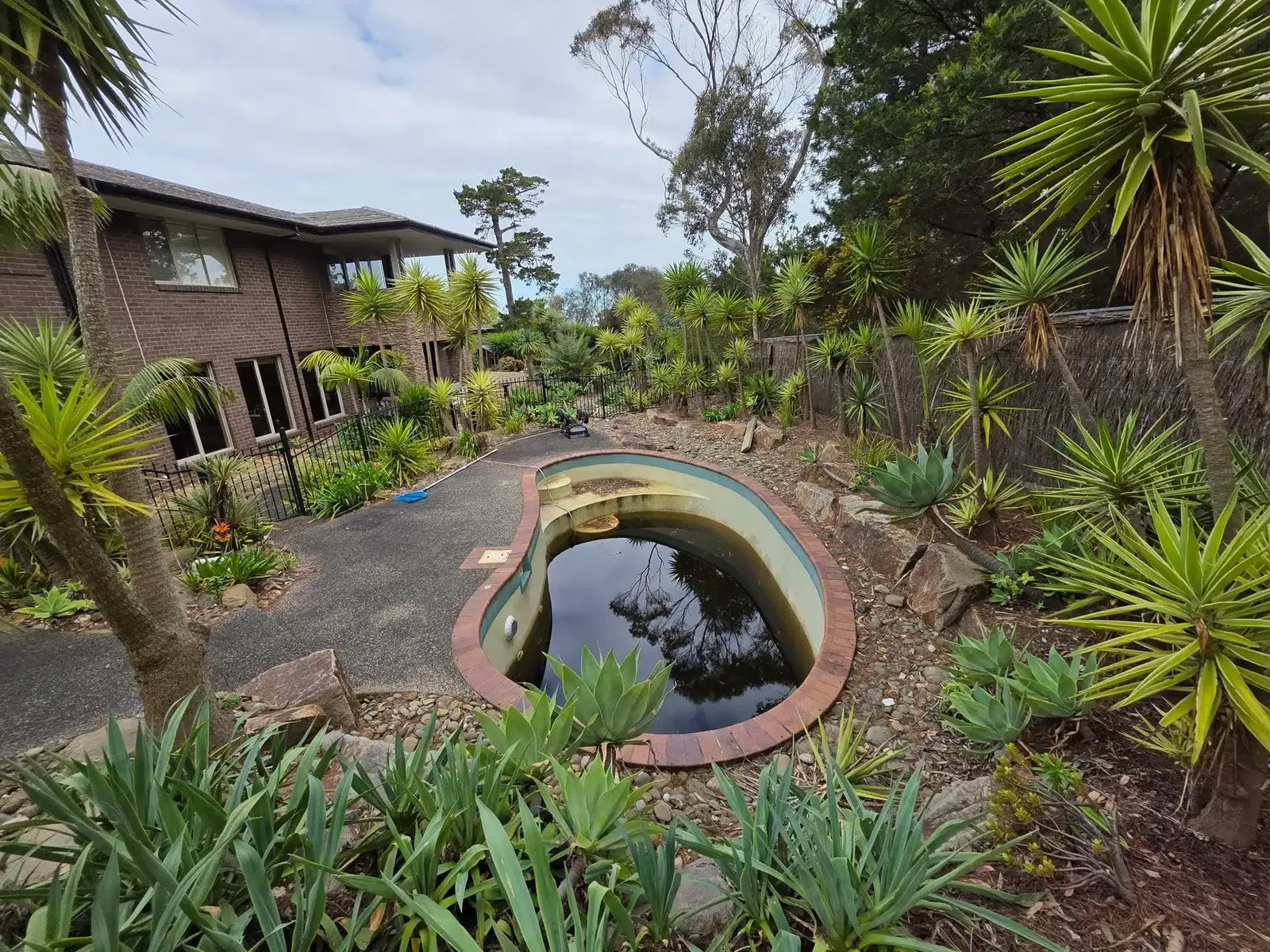 Small concrete pool in a landscaped garden before removal