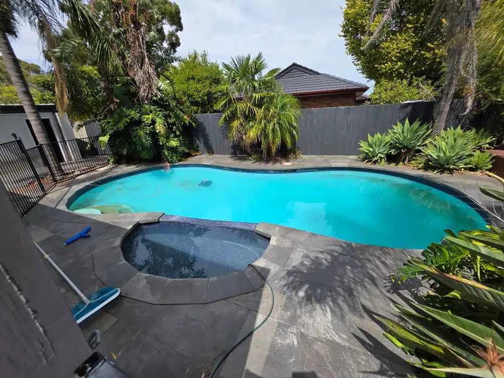 Before: concrete pool and spa in a backyard