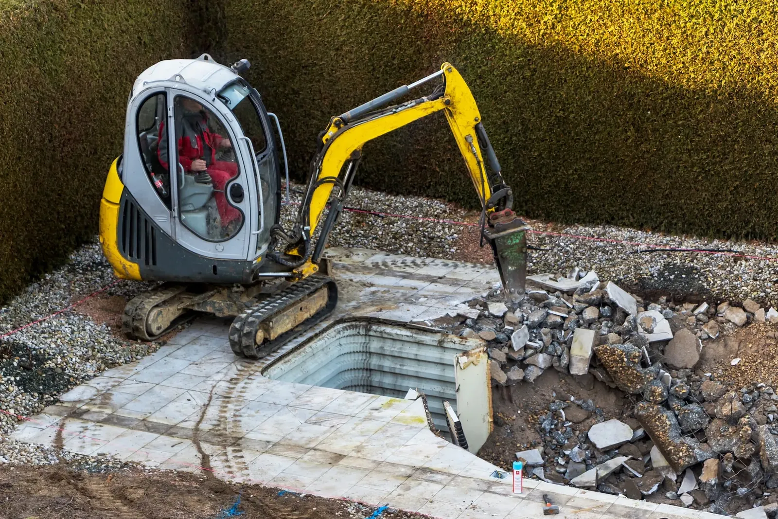 Mini excavator demolishing a pool and its surrounds