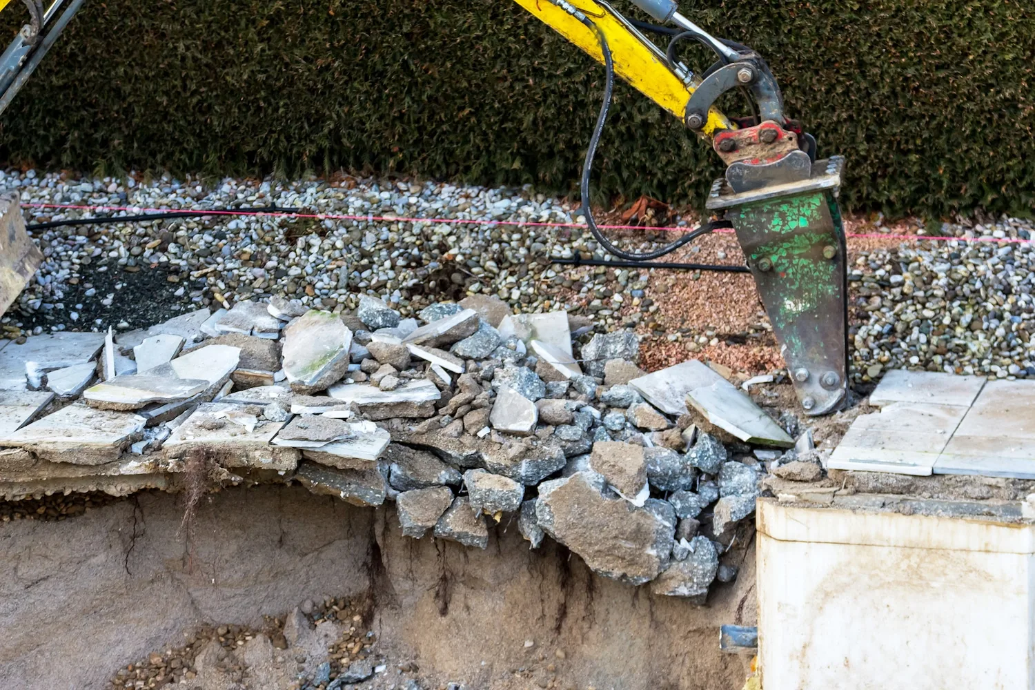 Hydraulic hammer breaking the wall of a concrete pool
