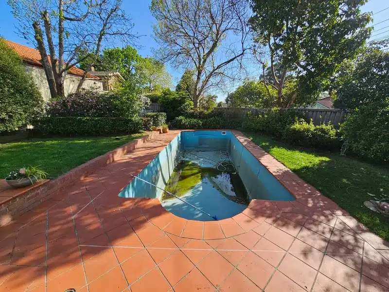 Before: green concrete pool with a terracotta-tiled surround