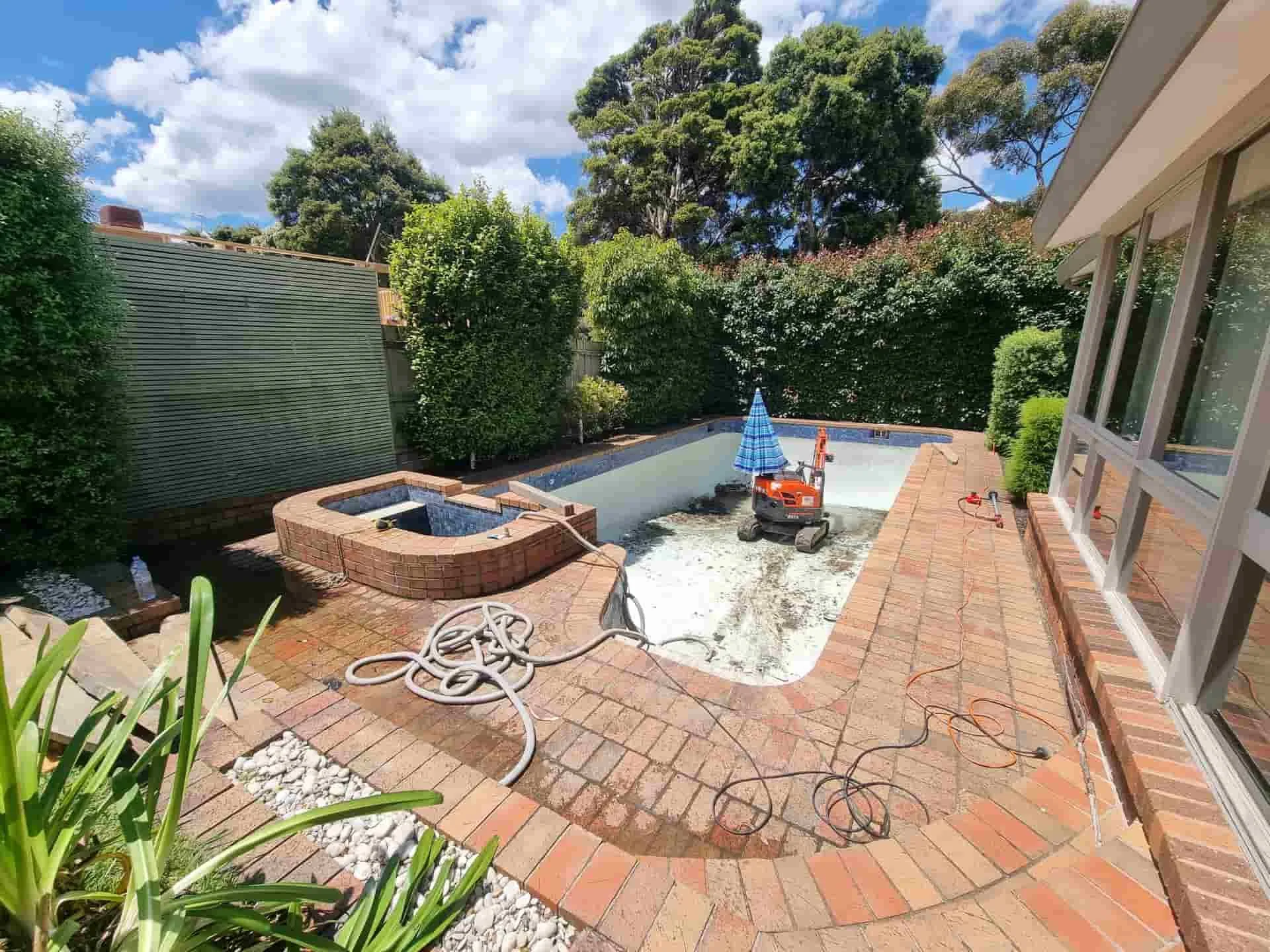 Swimming pool being removed from a brick-paved backyard